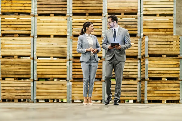 Full length of businesspeople walking around warehouse and monit